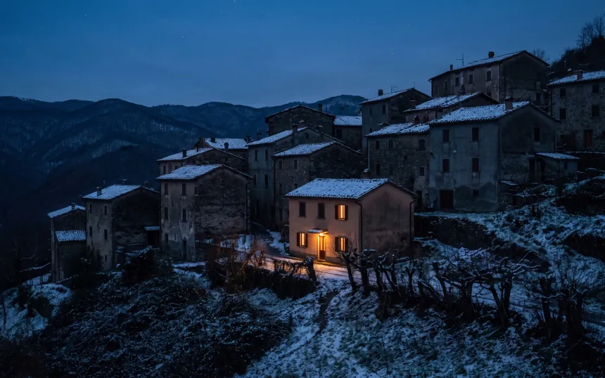 Borgo dell'Appennino al buio durante un blackout, una sola casa con le finestre accese